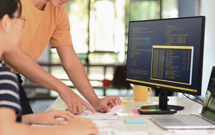 Student and teacher at a desk in front of a monitor