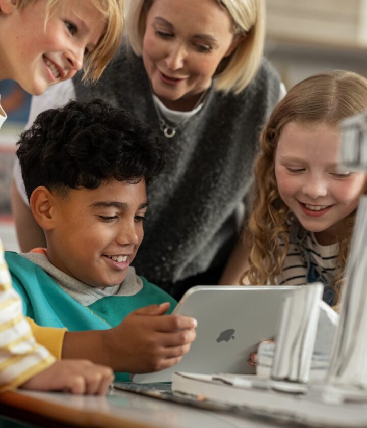 Teacher and students using a tablet for collaborative classroom learning.