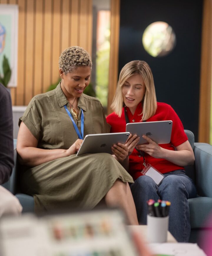 Two colleagues collaborating on tablets in a modern office.