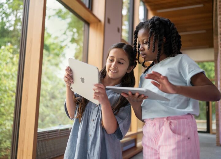 Two students collaborating with tablets in a modern learning space.
