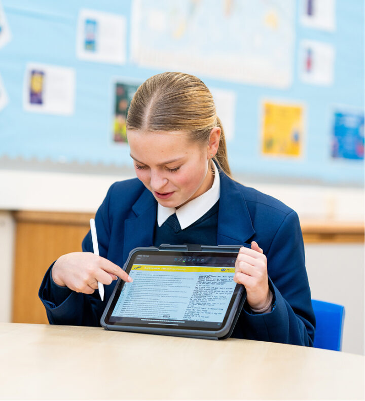Student using a tablet and stylus for digital learning in a classroom.